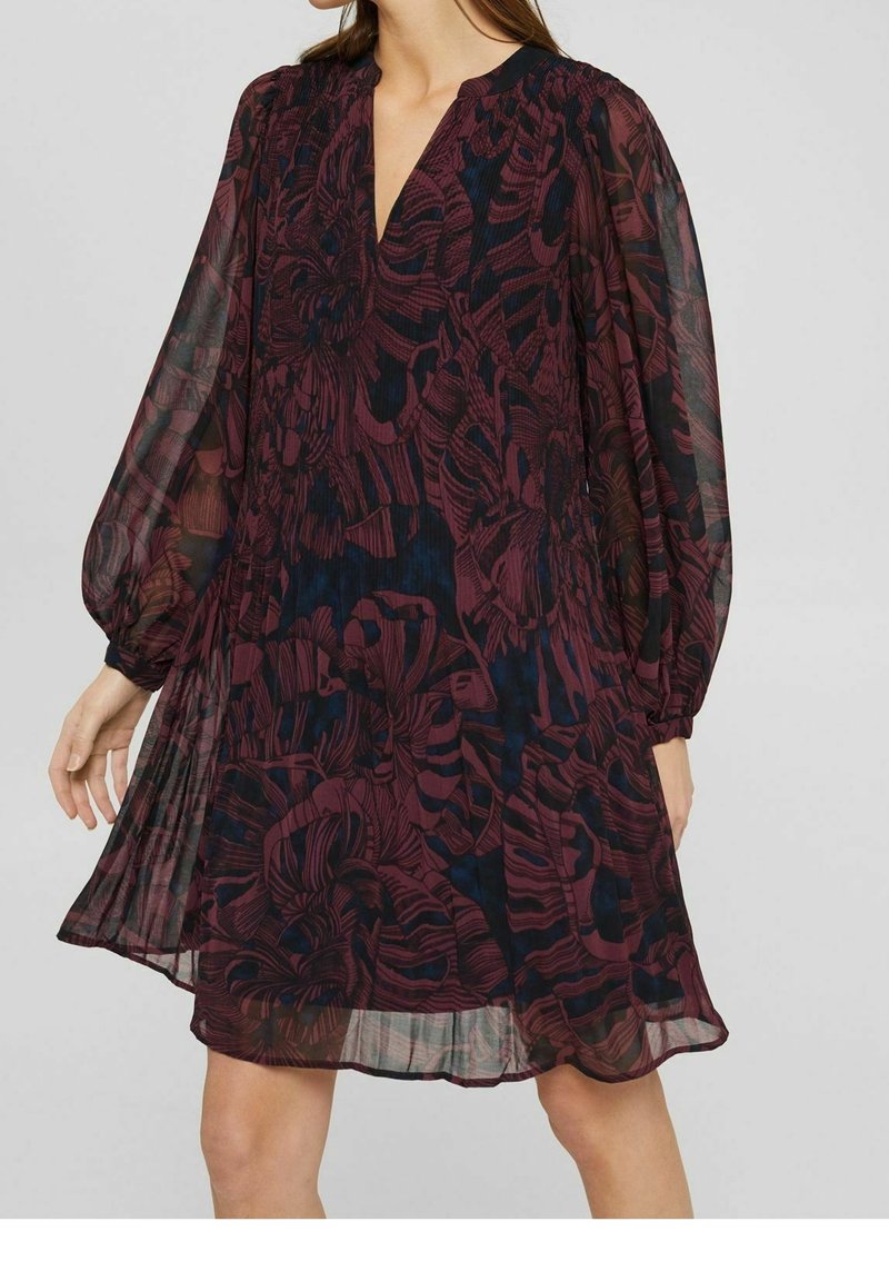 Långärmad bourgogny klänning med djup V-ringning, transparent tyg, blommönster och ett samlat midja, som flödar ner till en längd vid mitten av låret.