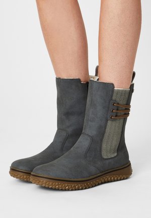 Bottines en suède grises avec une semelle en caoutchouc texturée, un panneau latéral à motifs pied-de-poule et des accents élastiques marron sur le dessus.