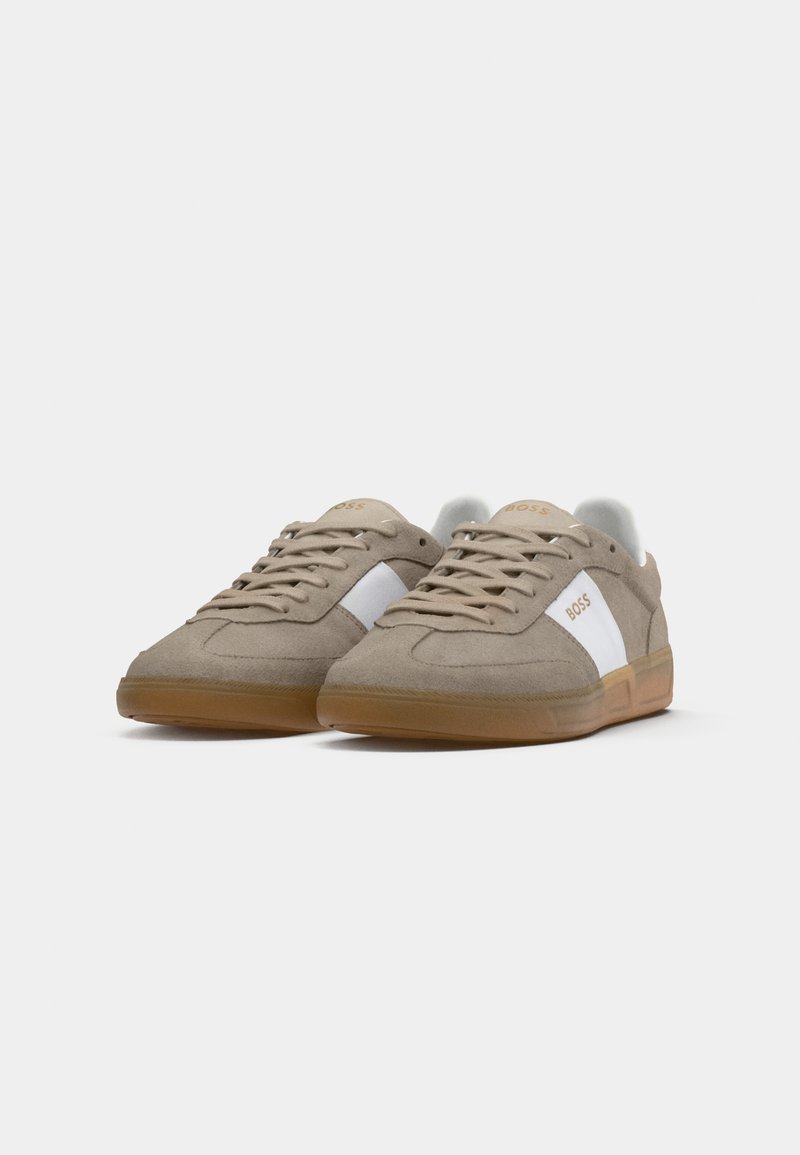 Sneakers in suede beige con accenti laterali bianchi e suole in gomma marrone. Caratterizzate da lacci piatti e logo sulla linguetta e sul pannello laterale.