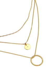 Collier multi-rangs en ton or comportant un cercle torsadé et un pendentif circulaire avec un motif estampé. Les chaînes varient en épaisseur et en texture.
