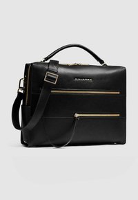 Zwarte leren boodschappentas met gouden ritsen, een bovenhandvat en een verstelbare schouderriem. Voorzien van voorzakken met rits en een gladde textuur.