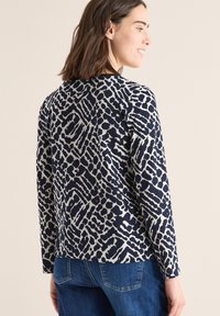 Marineblauwe longsleeve top met een crèmekleurig abstract patroon. Zachte stof, ronde hals, casual pasvorm en licht gebogen zoom.