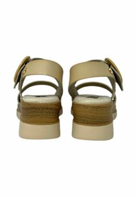 Sandali beige con tacco a blocco in stile legno, cinturini regolabili e accentuazione con fibbia rotonda, dotati di una tomaia in similpelle liscia.