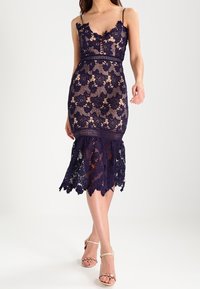 Námořnické krajkové šaty s květinovými vzory, přiléhavý korzet, nastavitelné ramínka, délka ke kolenům a detaily s vlnkovaným okrajem.