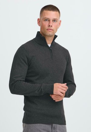 Dark gray zip-neck sweater made of textured fabric, featuring long sleeves and ribbed cuffs. Minimalist design with no visible patterns.
