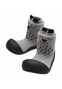 Calcetines de punto grises con una suela de goma negra, que presentan un diseño de cara sonriente y un patrón texturizado. De altura corta y un ajuste ceñido.