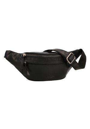 Mujer que lleva un bolso bandolera de cuero negro sobre un jersey blanco y vaqueros azul claro, vista desde atrás.