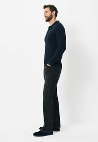 Marineblå langærmet polo skjorte med krave og tre-knaps placket, parret med sorte lige ben jeans og mørke casual sko.