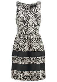 Robe sans manches noire et blanche avec des motifs tribaux géométriques et deux larges bandes horizontales noires unies près de l'ourlet.