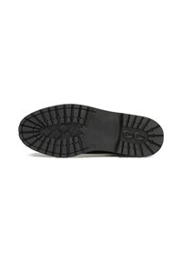 Semelle de chaussure en caoutchouc noir dotée d'un motif de crantage profond pour une meilleure adhérence, avec des bords arrondis et un logo discret sur le côté.