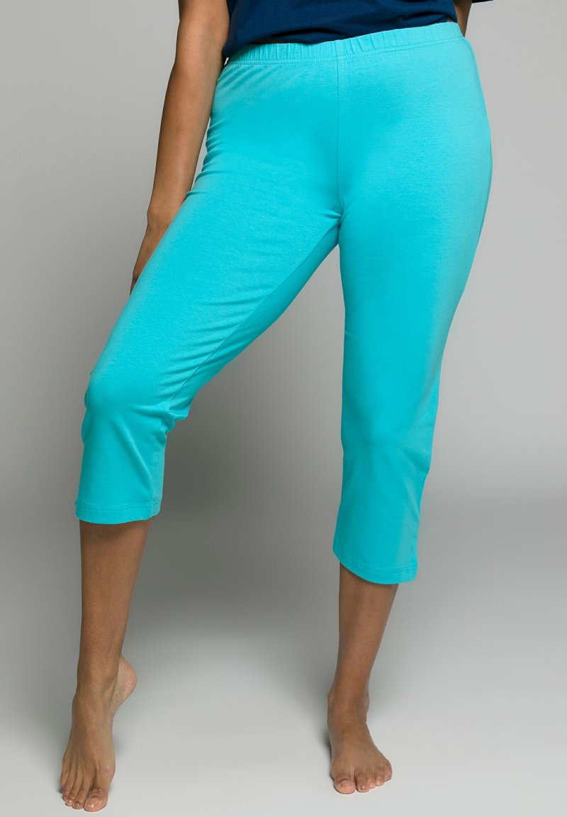 Tyrkysové capri kalhoty vyrobené z měkké, hladké textilie s elastickým pasem, se přiléhavým střihem končícími těsně pod kolenem.