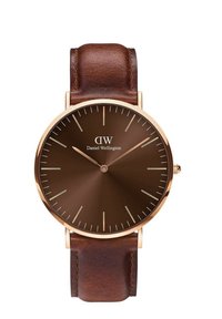 Brown leather strap wristwatch with a round brown dial, gold hour markers, and hands. Features a minimalist design with a brand logo.