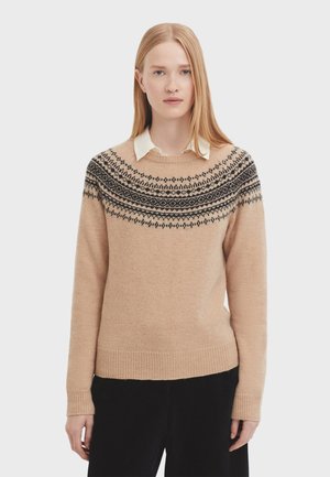 Beige knit sweater with a round neckline, featuring a black patterned yoke. Soft texture and ribbed cuffs and hem detail.