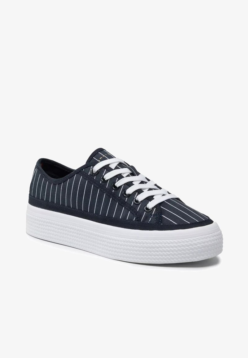 Sneaker in tela blu con strisce verticali bianche, lacci bianchi e suola in gomma bianca texturizzata. Design classico a bassa forma con punta rotonda.