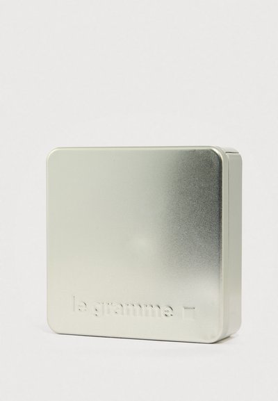 Kvadrātveida metāla konteineris ar gradienta apdari, ar gludu un spīdīgu virsmu; vienā pusē izspiedts uzraksts "le gramme".