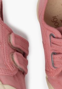 Scarpe di tela rosa con suole in gomma, dotate di chiusure a strappo e dettagli accattivanti. Forma arrotondata con tessuto texturizzato e cuciture a contrasto.