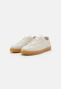 Vita lädersneakers med gummisulor, rund tå och platta snören. Har en diskret logotyp och sydda detaljer på sidorna.