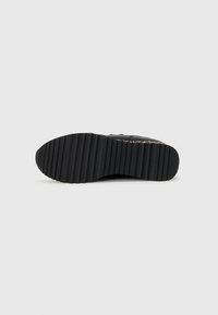 Sole di sneaker nera con un design strutturato. Presenta scanalature orizzontali e un'area superiore liscia, realizzata in gomma per una maggiore aderenza e durata.