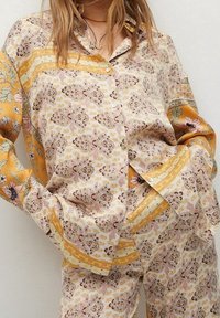Ensemble de pyjama en soie à motifs, crème, jaune et rose. Comprend des imprimés floraux, des boutons et des rayures contrastées sur les manches et le pantalon.