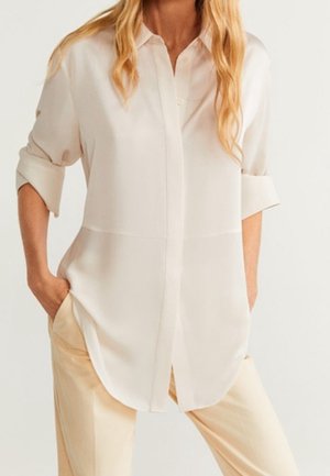 Vaaleanbeige pusero, jossa kauluksellinen pääntie, napillinen edusta ja käännetyt hihat. Valmistettu sileästä, kevyestä kankaasta, mukavan väljä istuvuus.