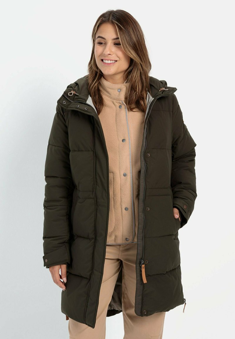 Mørkegrøn pufferjakke med hætte, der har lynlås og trykknaplukning, frontlommer og brune detaljer. Bæres over en beige fleece-trøje.