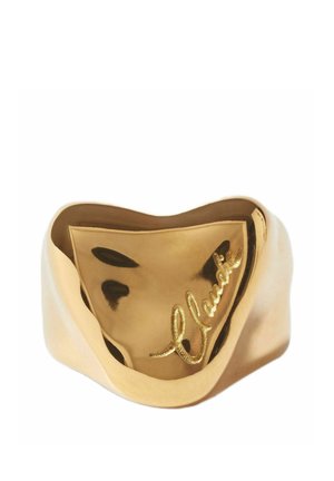 Anello largo in oro con superficie ondulata e riflettente e firma incisa in corsivo sul davanti.