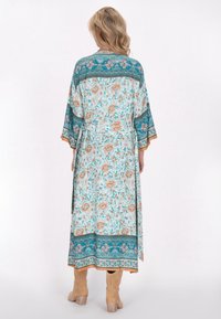 Kimono floreale lungo con un motivo turchese e beige, dotato di maniche ampie, vita cinte e bordi decorativi lungo l'orlo.