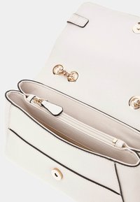 Hvid læderhandbag med en tekstureret overflade, sorte accenter, guldfarvet hardware og en indvendig lynlåslomme. Klaplukning med magnetlås.