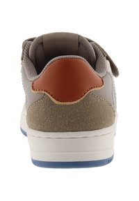Grijze en beige sneaker met een suède afwerking, leren accent op de hiel en een witte rubberen zool met blauwe details. Klittenbandsluiting aan de voorkant.