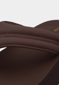 Καφέ σανδάλι από αφρό με παχιά επενδεδυμένα λουράκια και ελαφρώς ανυψωμένη σόλα, σχεδιασμένο για καθημερινή χρήση.