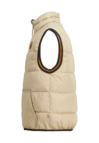 Beige-päällysteinen liivi korkealla kauluksella, käsivarsia varten leikkaukset ja vastakkaiset mustat ja oranssit vuoraukset. Sisältää sivutaskun ja vaakasaumat.