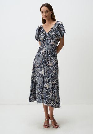 Robe bleue marine à motifs floraux, à manches courtes et décolleté en V, confectionnée en tissu léger, tombant jusqu'aux mi-mollets. Sandales argentées.