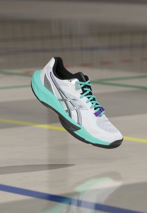 Weißer und türkisfarbener Sportschuh mit schwarzer Sohle und türkisfarbenen Schnürsenkeln, schwebend über einem Hallenboden mit bunten Spielfeldlinien.