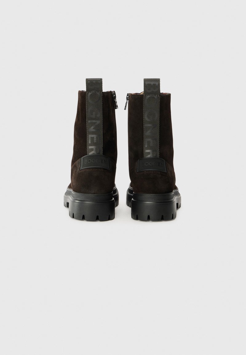 Ein Paar dunkelbraune Wildlederstiefel mit dicken schwarzen Sohlen, einem Reißverschluss auf der Rückseite und markierten Ziehschlaufen mit der Aufschrift "BOGNER", der hinten zeigt.