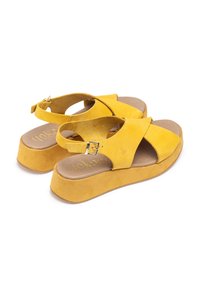 Gelbe Wildleder-Wedge-Sandalen mit Querriemen-Design und verstellbarem Knöchelriemen. Weiches braunes Fußbett und strukturierte Plattformsohle.