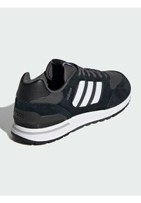 Baskets de sport noires et grises en matériaux daim et mesh, avec trois rayures blanches, semelle rembourrée et semelle en caoutchouc pour l'adhérence.