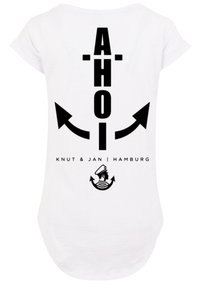 White t-shirt featuring black graphics. Text "AHOI" with arrow designs above, brand name beneath, and anchor motif at the bottom.