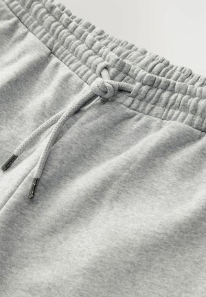 Grijze trainingsbroek met een elastische tailleband, voorzien van een trekkoord met metalen tips. Zacht, gestructureerd materiaal met een gladde afwerking.