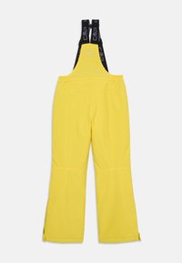 Keltaiset lumihousut, joissa on säädettävät mustat hihnat, leveät lahkeet ja huomaamaton ompelu. Etuhihnassa ja sivuvetoketjuissa on CMP-logo.