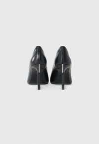 Pair of black leather high-heeled pumps shown from the back with slim stiletto heels against a plain white background.