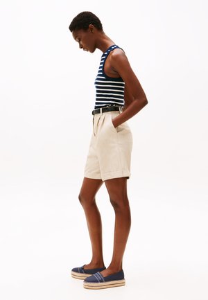 Randig marinblå och vit tanktopp, beige skräddarsydda shorts med uppvikta fållar, svart bälte, marinblå slip-on espadriller med jutesula.