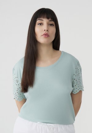 T-shirt azzurro chiaro con maniche corte a motivo pizzo. Texture liscia e scollatura rotonda, con una silhouette aderente.