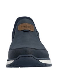 Chaussure à enfiler marine en cuir à finition texturée, avec un patch de marque marron et une semelle en caoutchouc blanche avec des accents noirs.