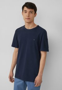 Marineblauw katoenen T-shirt met korte mouwen, ronde hals en een klein logo-opdruk op de linkerkant van de borst. Eenvoudig ontwerp, zachte textuur.