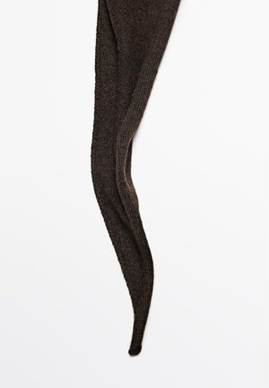 Brune strikkede strømpebukser med en ribbet tekstur. Stoffet er blødt og har en tilspidset ende, designet til at give et tætsiddende look.