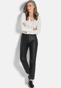 Pantalons en cuir noirs à taille haute et coupe slim, associés à une chemise blanche à manches longues et des baskets noires. Texture lisse, design minimal.