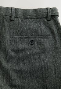 Grey herringbone trousers with a buttoned back pocket, belt loops, and a textured fabric. Features vertical stripes and subtle detailing.
