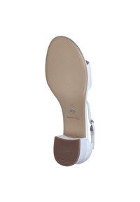 White high-heeled sandal with a rounded toe, textured upper, and a brown rubber sole featuring grip lines. Adjustable ankle strap included.