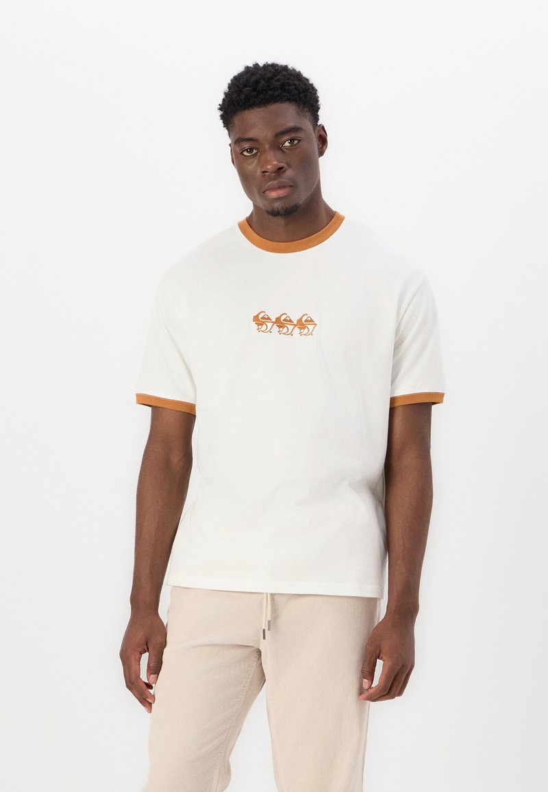 Camiseta blanca de algodón con un cuello y puños de manga acanalados en marrón. Presenta un diseño impreso de tres ranas estilizadas en el pecho.