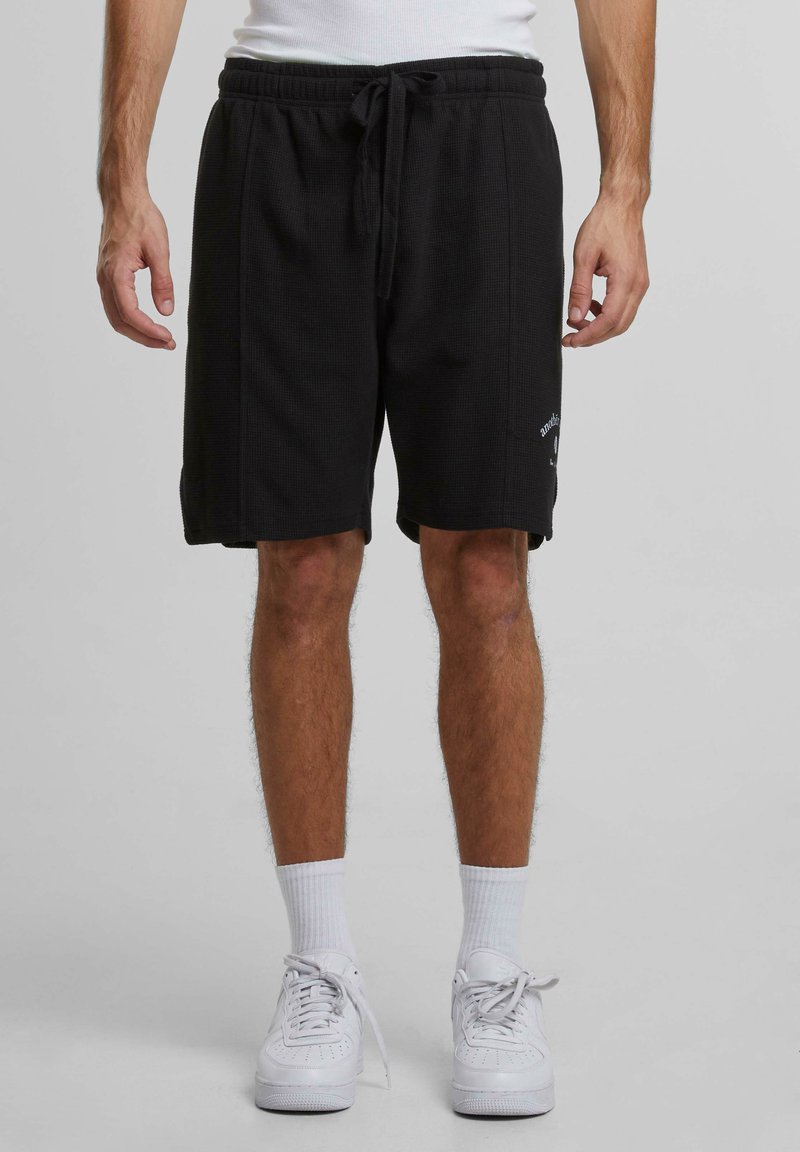 Svarta bomullsshorts med texturerad väv, elastisk midja och dragsko. Har sidofickor och logodetalj på vänster ben.